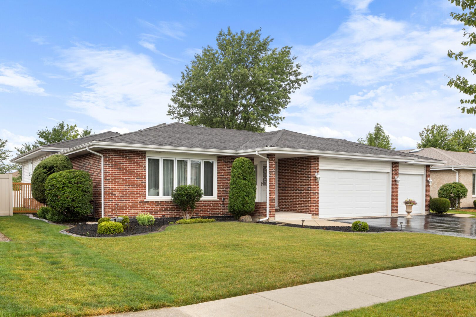 Brick house with garage and manicured lawn.