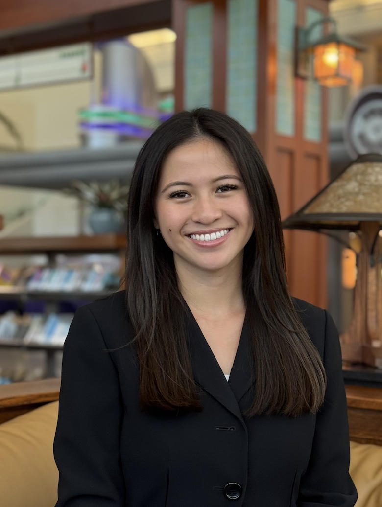 Smiling woman with long dark hair in a cozy indoor setting.
