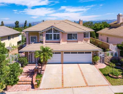 Spacious two-story suburban house with a three-car garage and palm trees.