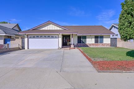 Single-story house with a two-car garage and a front lawn under a clear blue sky.