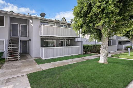 Modern townhouse with gray exterior and green lawn under clear sky.