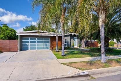 Modern single-story house with palm trees and a spacious driveway.