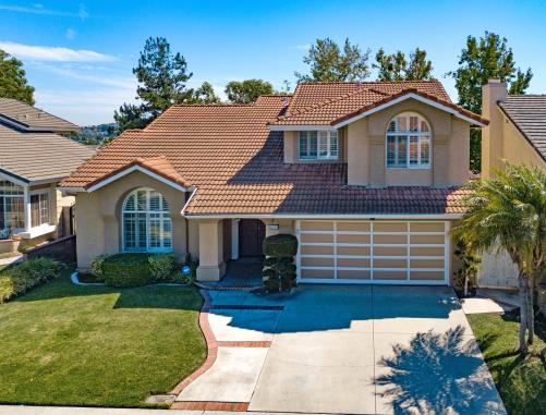 A beautiful suburban house with a manicured lawn and clear blue sky.