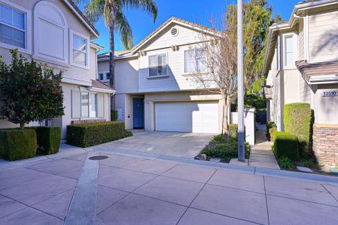 Modern two-story house with garage and driveway in sunny neighborhood.