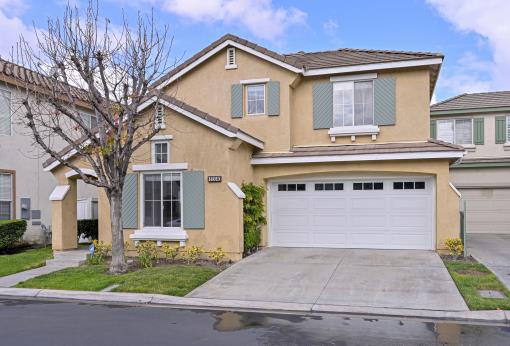 Two-story suburban house with a two-car garage and a leafless tree.