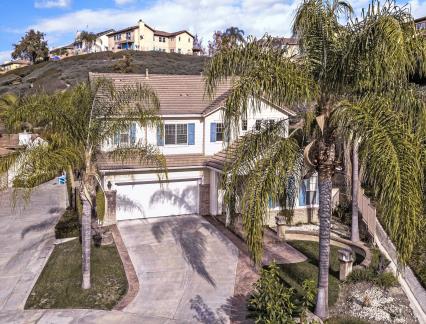 A two-story house with palm trees and a driveway in front.