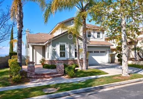 Sunny suburban house with palm trees and a two-car garage.