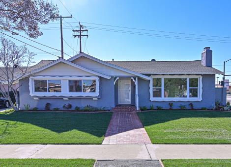 Single-story blue house with a well-maintained lawn and clear sky.