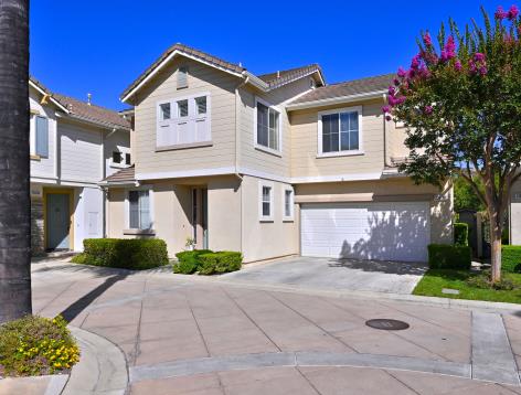 Modern townhouse with beige exterior and attached garage under clear sky.