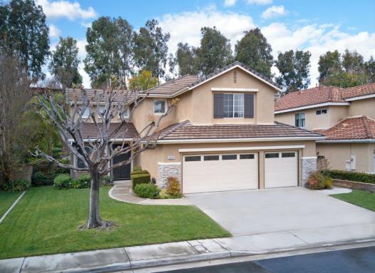 A two-story suburban house with a three-car garage and a small tree in the front yard.