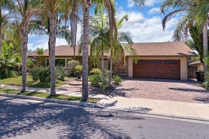 Single-story house with palm trees and a brick driveway.