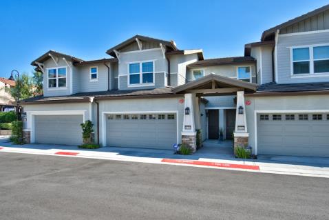 Modern townhouse with attached garages under a clear blue sky.
