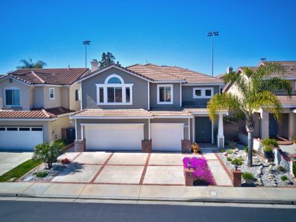 Modern suburban house with a three-car garage and palm trees.