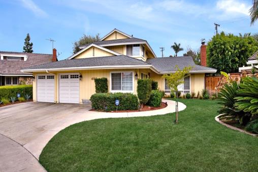 Bright suburban house with a well-maintained lawn and driveway.