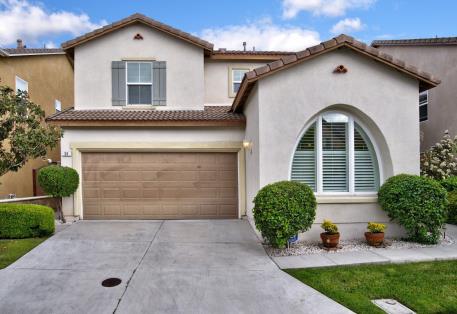 Modern two-story house with a wooden garage door and neatly trimmed bushes.