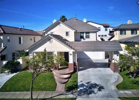 A modern suburban house with a well-kept lawn and clear blue sky.