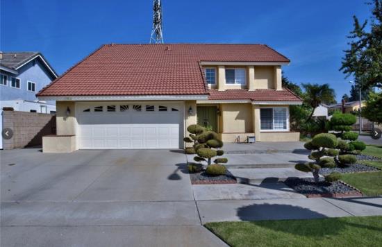 Two-story house with a red roof and a manicured front yard.