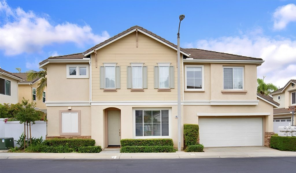 Modern townhouse with beige exterior and garage in a suburban neighborhood.