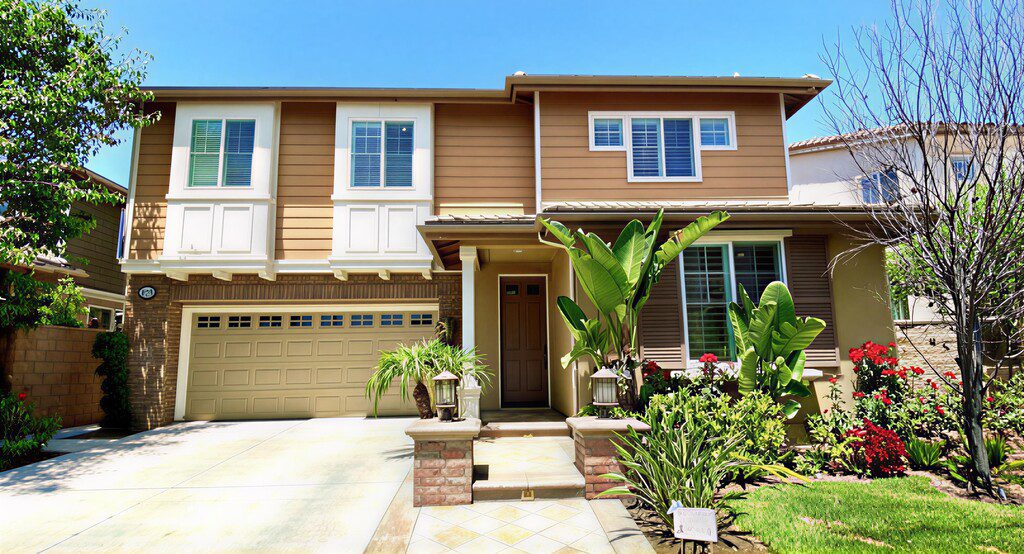 Modern townhouse with a front garden and driveway under a clear blue sky.