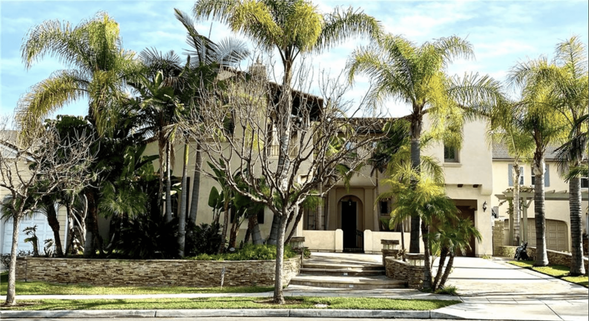 A large house surrounded by palm trees and a clear sky.