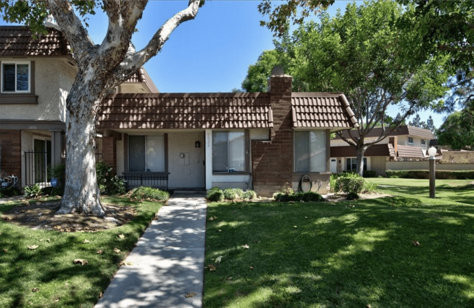 Small single-story brick house with a tiled roof and green lawn.