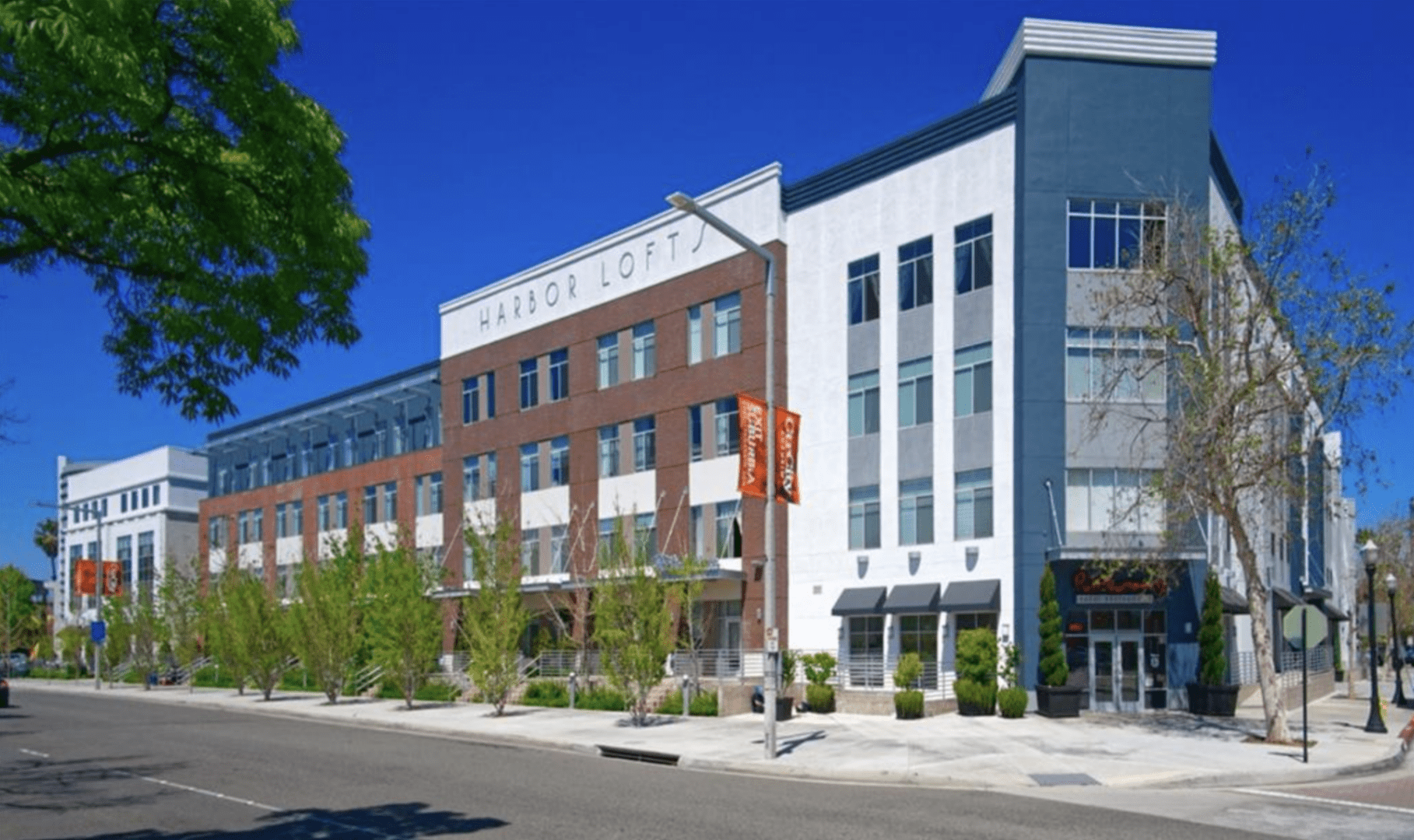 Modern mixed-use building with shops and apartments on a sunny day.