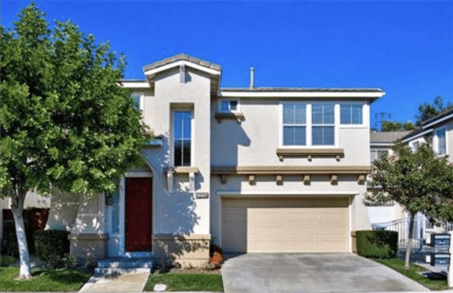 Modern two-story house with a red front door and a two-car garage.