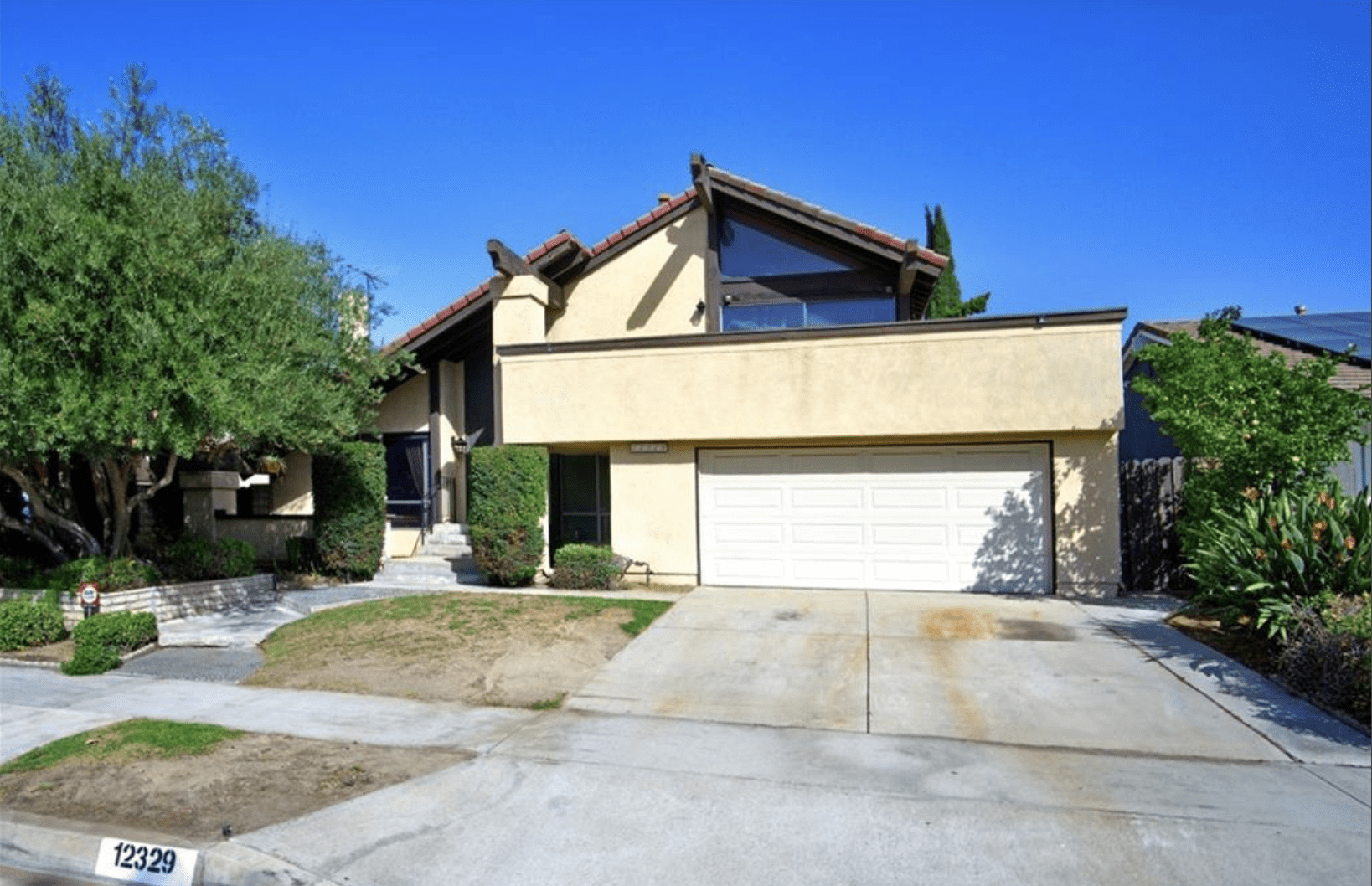Suburban two-story house with garage and front lawn.