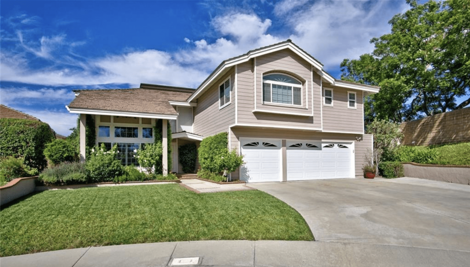 Modern two-story house with a three-car garage and manicured lawn.