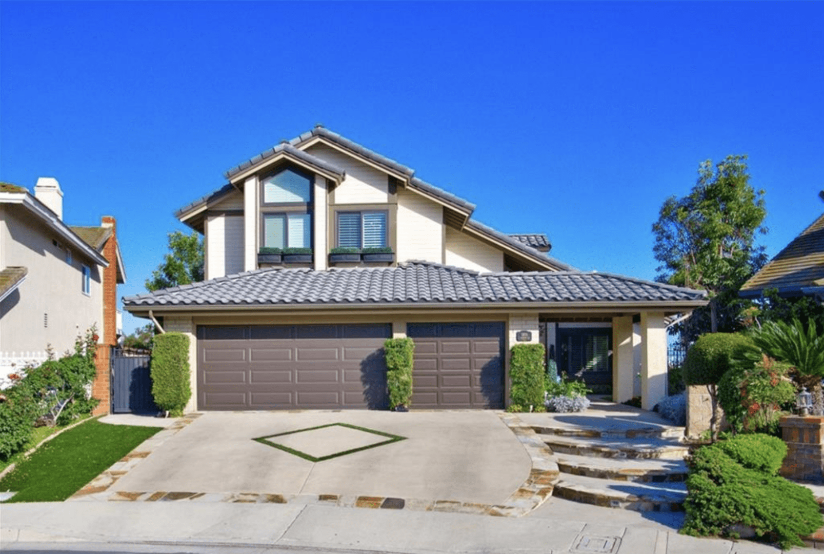 Modern two-story house with a three-car garage and a clear blue sky.