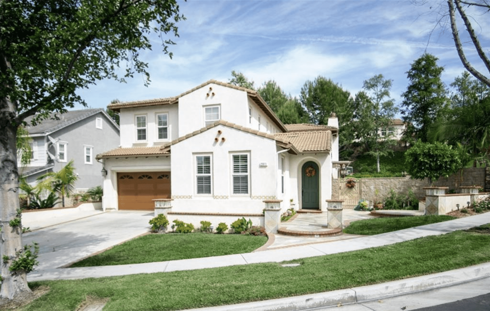 A modern two-story house with a beige exterior and well-kept lawn.