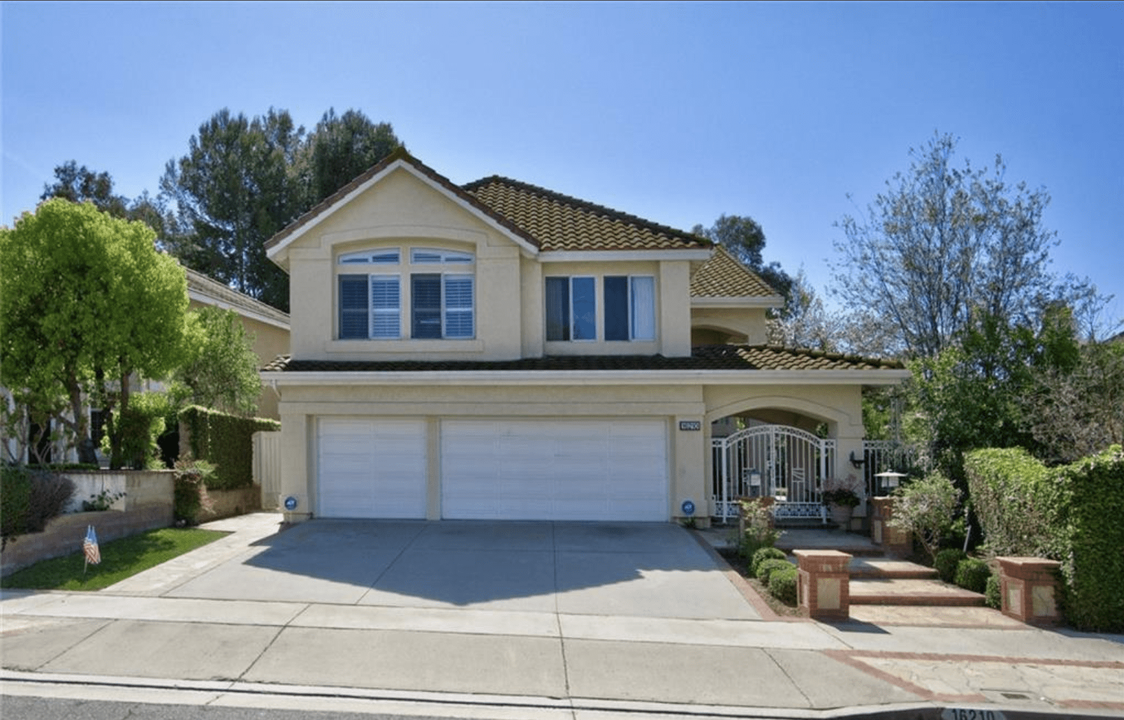 Two-story suburban house with a three-car garage and a well-kept front yard.